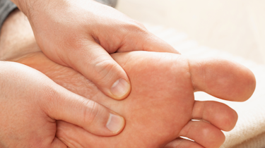 руки торкаються стопи та щиколотки як ілюстрація до матеріалу про діагностику оніміння стопи у клініці Медонія Прайм