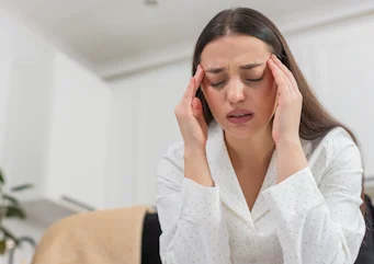жінка торкається голови через інтенсивний біль як ілюстрація до матеріалу про кластерний головний біль та обстеження причин у клініці Медонія Прайм