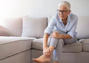 літня людина торкається ноги через болісний спазм як ілюстрація до матеріалу про причини судом ніг у літніх людей та лікування в клініці Медонія Прайм