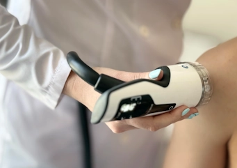 Лікар проводить процедуру радіальної ударно-хвильової терапії пацієнту у Медонії Прайм