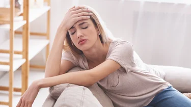 світловолоса жінка тримається за лоб через запаморочення як ілюстрація до матеріалу про лікування запаморочення у жінок в клініці Медонія Прайм