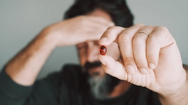 чоловік тримає таблетку в руці як ілюстрація до матеріалу про підбір лікування при головному болю в клініці Медонія Прайм