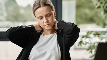 жінка тримається за шию через дискомфорт і головний біль як ілюстрація до матеріалу про кластерний головний біль в клініці Медонія Прайм