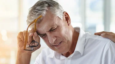 чоловік старшого віку з поганим самопочуттям тримається за скроню як ілюстрація до матеріалу про допомогу при запамороченні та нудоті у клініці Медонія Прайм