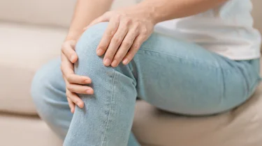 людина в джинсах тримається за коліно через спазм у нозі як ілюстрація до матеріалу про судоми ніг після навантаження в клініці Медонія Прайм