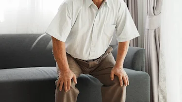 літня людина сидить і тримається за коліна як ілюстрація до матеріалу про судоми ніг і слабкість у літніх людей в клініці Медонія Прайм