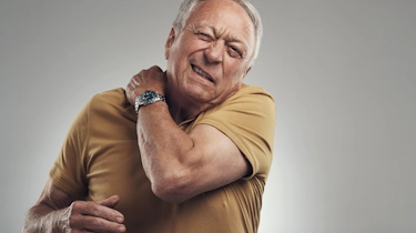 літній чоловік тримається за плече і шию через біль як ілюстрація до матеріалу про відновлення при остеохондрозі у клініці Медонія Прайм