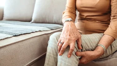 людина торкається ноги через неприємні відчуття як ілюстрація до матеріалу про діагностику болю в ногах при хронічній ішемії нижніх кінцівок в клініці Медонія Прайм