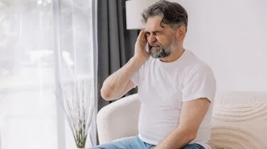 чоловік тримається за скроню через сильний біль у ділянці скронь як ілюстрація до матеріалу про діагностику головного болю в клініці Медонія Прайм