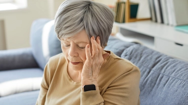 жінка тримається за скроню через погане самопочуття як ілюстрація до матеріалу про симптоми набутої епілепсії в клініці Медонія Прайм