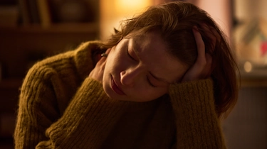 жінка лежить із рукою на голові через сильний головний біль як ілюстрація до матеріалу про причини головного болю та обстеження в клініці Медонія Прайм