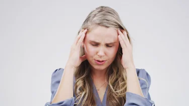 молода жінка тримається за скроні через сильний головний біль як ілюстрація до матеріалу про кластерний головний біль в клініці Медонія Прайм