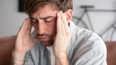 чоловік тримається за скроні через сильний головний біль як ілюстрація до матеріалу про діагностику кластерного головного болю у чоловіків в клініці Медонія Прайм