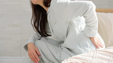 жінка тримається за спину через неприємні відчуття як ілюстрація до матеріалу про консультацію при радикуліті в клініці Медонія Прайм