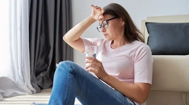 жінка тримає таблетку і торкається голови через сильний біль як ілюстрація до матеріалу про консультацію при кластерному головному болю на тлі стресу в клініці Медонія Прайм