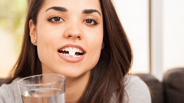 жінка тримає склянку води як ілюстрація до матеріалу про вибір препаратів від головного болю у клініці Медонія Прайм