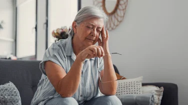 літня жінка тримається за скроню через дискомфорт як ілюстрація до матеріалу про діагностику набутої епілепсії у старшому віці в клініці Медонія Прайм