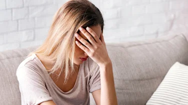 жінка сидить із сильним головним болем як ілюстрація до матеріалу про лікування симптомів кластерного головного болю в клініці Медонія Прайм