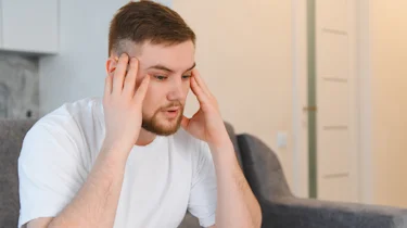 молодий чоловік тримається за скроні через сильний головний біль як ілюстрація до матеріалу про кластерний головний біль в клініці Медонія Прайм
