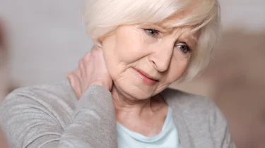 літня жінка тримається за шию через біль як ілюстрація до матеріалу про діагностику болю в шиї у клініці Медонія Прайм