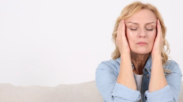 жінка із заплющеними очима тримається за скроні через сильний головний біль як ілюстрація до сторінки про головний біль з нудотою та запамороченням у клініці Медонія Прайм у Хмельницькому