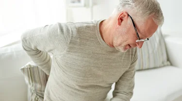 чоловік тримається за поперек через сильний біль як ілюстрація до матеріалу про симптоми радикуліту та діагностику в клініці Медонія Прайм