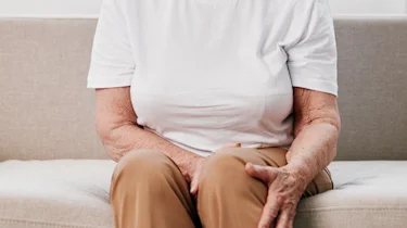 людина сидить і тримається за ноги як ілюстрація до матеріалу про хронічну ішемію нижніх кінцівок та біль у ногах в клініці Медонія Прайм