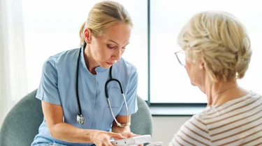 медпрацівниця консультує літню жінку як ілюстрація до матеріалу про підтримку пацієнтів із хворобою Паркінсона у клініці Медонія Прайм