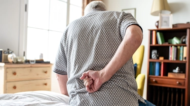 людина стоїть нахилившись і тримається за поперек через біль як ілюстрація до матеріалу про діагностику спондилоартрозу попереку у клініці Медонія Прайм