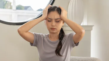 жінка тримається за голову через тривалий біль як ілюстрація до матеріалу про діагностику хронічного болю в голові в клініці Медонія Прайм