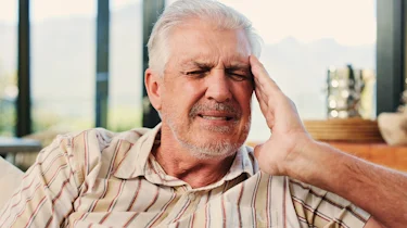чоловік старшого віку тримається за скроню через інтенсивний головний біль як ілюстрація до матеріалу про діагностику сильного головного болю в клініці Медонія Прайм