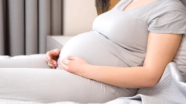 вагітна жінка тримається за скроню через сильний головний біль як ілюстрація до матеріалу про діагностику та рекомендації при головному болю під час вагітності у клініці Медонія Прайм